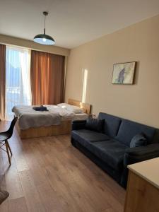 ein Wohnzimmer mit einem Bett und einer Couch in der Unterkunft New Gudauri, Alpic - Ski Resort at Your Doorstep - Stylish & Comfy Ski Apartment with ski-depot and Stunning Mountain Views in Gudauri