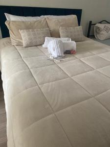 a large white bed with a stuffed animal on it at Pousada Le Sorelle apt03 in Rosário do Sul