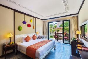 ein Hotelzimmer mit einem Bett und einem Balkon in der Unterkunft Cozy Hoian Villas Boutique Hotel in Hoi An