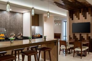 a kitchen with a bar with chairs and a tv at Marriott DFW Airport South in Fort Worth