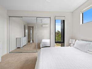 a bedroom with a large white bed and a mirror at Wirilda Retreat in Inverloch +24 photos