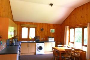 a kitchen with wooden walls and a table with chairs at Plodda Lodge at Lochletter Lodges in Drumnadrochit