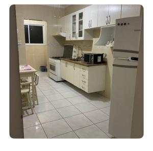 a kitchen with white appliances and a table in it at Apartamento aconchegante in Praia Grande