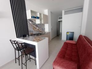 a kitchen and a living room with a red couch at Apartaestudios Típica Loft in Pasto