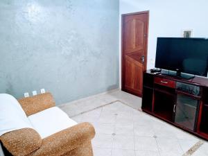 uma sala de estar com um sofá e uma TV de tela plana em Apartamento Vip no Frade em Angra dos Reis