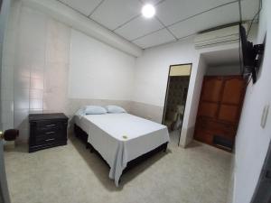 a bedroom with a white bed and a wooden door at Apartamento Jarhel in Aguachica