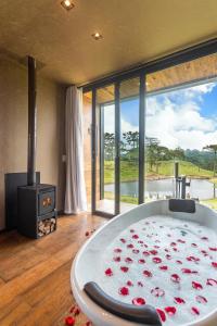 eine Badewanne mit Rosen in einem Zimmer mit Kamin in der Unterkunft Brumas Casa de Campo - Cambará do Sul in Cambará