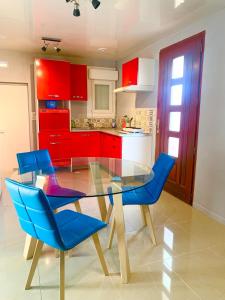 a kitchen with a glass table and blue chairs at Maison entière entre Orléans et Montargis in Chailly-en-Gâtinais