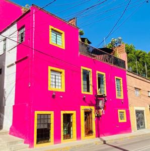 Un edificio rosa con ventanas amarillas en una calle. en Hotel El Andariego, en Oaxaca City