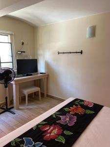 Habitación con escritorio y cama con alfombra de flores. en Hotel El Andariego, en Oaxaca City