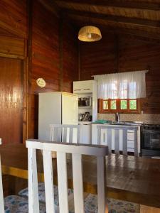 a kitchen with white appliances and a white table at CASA GAMBOA BEACH in Garopaba