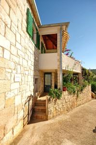 a stone house with a green door and stairs at Apartments Kat in Splitska