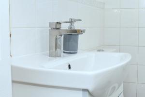 a white sink in a white tiled bathroom at Tranquil Stays at 3 bedroom House in Dagenham in Dagenham +54 photos
