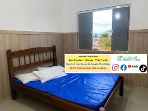 ein Bett mit blauer Bettwäsche und ein Fenster in einem Zimmer in der Unterkunft Cabo Frio - Parque Burle - Aluguel Econômico in Cabo Frio