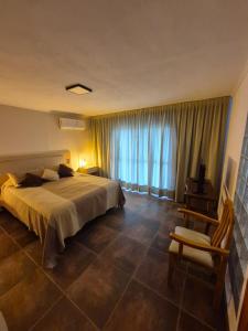 a bedroom with a bed and a chair and a window at Mirada al Champaqui - Departamento de Montaña in Villa Yacanto