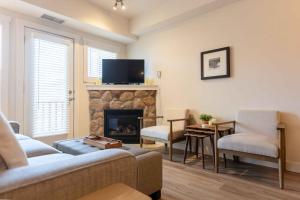 Silver Rock Condominiums by Fernie Central Reservations في فيرني: غرفة معيشة مع أريكة ومدفأة