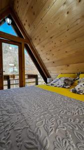 a bed in a room with a wooden ceiling at Wooden House ŠUŠKA 3 - Drvena kuća ŠUŠKA 3 in Zaovine