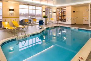 a pool in a hotel room with yellow chairs at Fairfield Inn & Suites by Marriott Utica in Utica