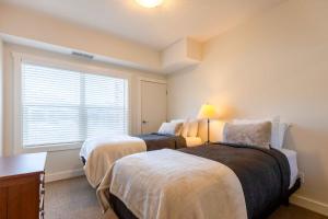 Silver Rock Condominiums by Fernie Central Reservations في فيرني: سريرين في غرفة بها نافذة