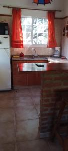 a kitchen with a sink and a white refrigerator at Cabañas El Duende in Quines
