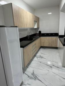 Il comprend une cuisine dotée d'un sol en marbre blanc et d'un réfrigérateur blanc. dans l'établissement Villa Serenità, à Peruíbe