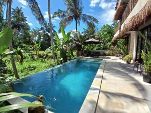 a swimming pool in front of a house with palm trees at Bali View Ubud Hotel in Ubud