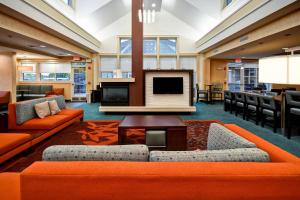 a lobby with orange furniture and a flat screen tv at Residence Inn by Marriott Springfield Chicopee in Chicopee