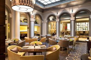a restaurant with tables and chairs and a chandelier at Paris Marriott Opera Ambassador Hotel in Paris