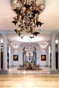パリにあるパリス マリオット オペラ アンバサダー ホテルの大きなシャンデリアが天井から吊るされている大きな部屋(テーブル付)