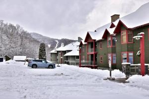 a car parked in front of a house in the snow at Lodges at Sunrise 3BR 3BA Luxury Ski On Ski Off Condo, Pool, Hot Tub, Gym, Sports Center in Killington