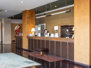 a woman sitting at a bar in a hotel lobby at Hotel Fujiyoshi in Beppu
