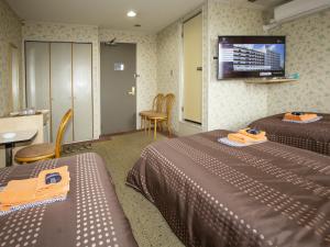 a hotel room with two beds and a flat screen tv at Hotel Fujiyoshi in Beppu
