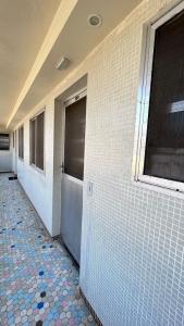 a bathroom with white tiled walls and a tile floor at apartment 1 bedroom in Mongaguá +1 photo