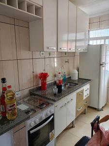 a kitchen with white cabinets and a stove top oven at apartment 1 bedroom in Mongaguá