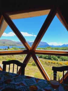 a table with a view of the mountains from a window at Domo Kumelén Mahuida in Junín de los Andes