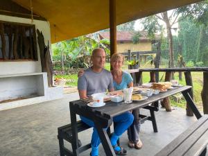 a man and a woman sitting at a picnic table at Sinharaja Riverside in Deniyaya