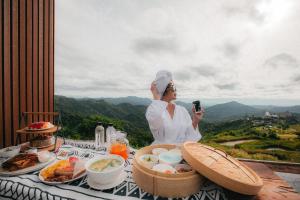 een vrouw die een foto neemt van een tafel met eten bij The Pino Khao Kho in Phetchabun