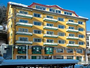 un edificio giallo con la neve davanti di Spacious apartment with mountain view a Bad Gastein
