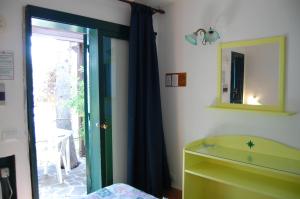 a bedroom with a green door and a mirror at Hotel Club Torre Capovento in Sperlonga