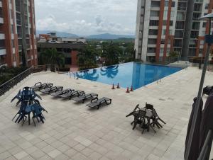eine Gruppe von Tischen und Stühlen neben einem Swimmingpool in der Unterkunft Apartaestudio Vacacional en Girardot, piscinas, Jacuzis, parqueadero para moto in Girardot + 2 Fotos