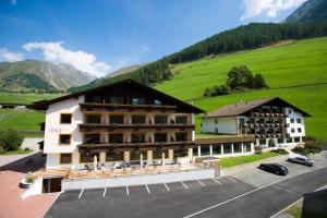 un gran hotel con una colina verde en el fondo en Berghotel Tyrol, en Senales