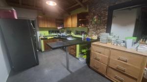a kitchen with wooden cabinets and a black refrigerator at Iraka Campestre Quindio in El Edén