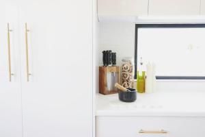 a white kitchen with a mirror and a counter top at The Arv in Robe +39 photos