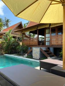 a house with a swimming pool and a yellow umbrella at Villa Gong bali in Ubud