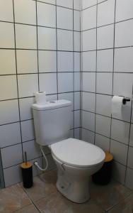 a white toilet in a bathroom with white tiles at Casa Ori Lar Boipeba in Ilha de Boipeba