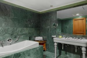 a green bathroom with two sinks and a tub at Rome Marriott Park Hotel in Rome
