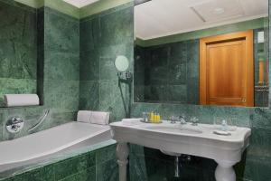 a green tiled bathroom with a sink and a tub at Rome Marriott Park Hotel in Rome