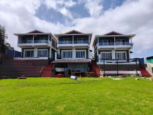 a large house with a lawn in front of it at Longwood Resorts in Kotagiri