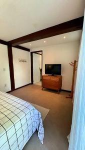 a bedroom with a bed and a flat screen tv at Sun House Manguinhos in Búzios