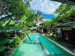 a swimming pool in front of a house with trees at Ubud Kerta Prashati in Ubud